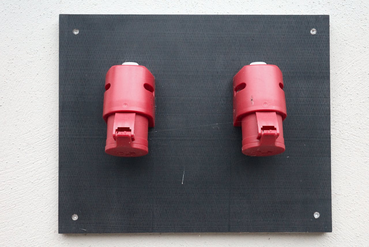 why-choose-us Image of two red industrial electrical connectors mounted on a wall.