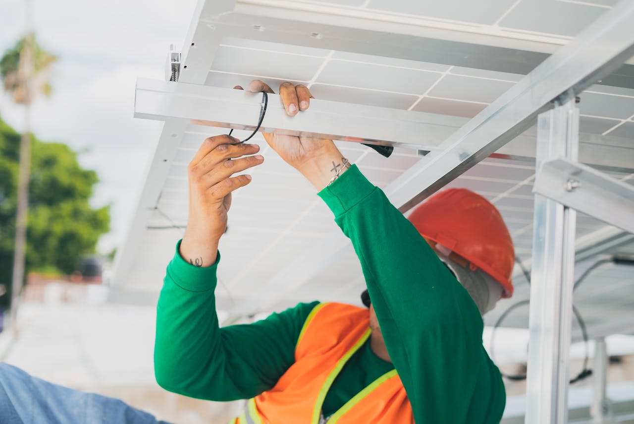 services-01 A solar technician in PPE installs a solar panel, showcasing renewable energy work.